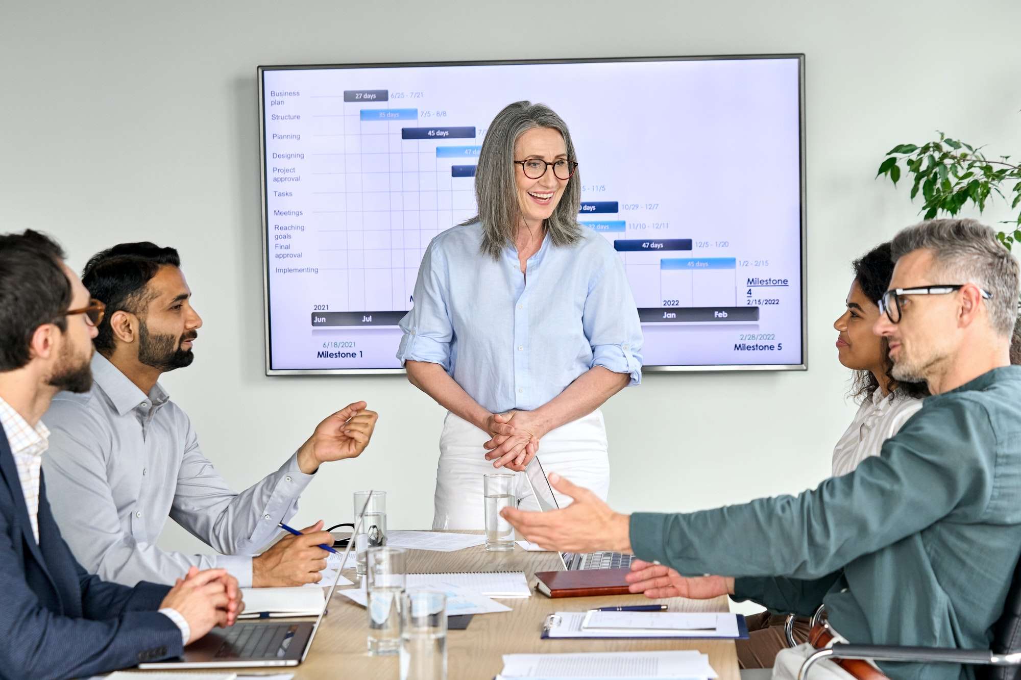 Happy diverse corporate team having presentation in boardroom office.