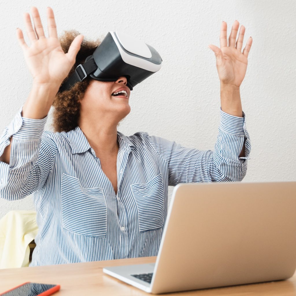 Senior african woman using vr virtual reality headset at home office - Technology business trend