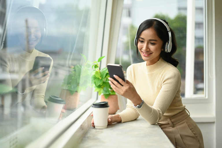 Attractive woman drinking coffee and chatting with friends on mobile phone.