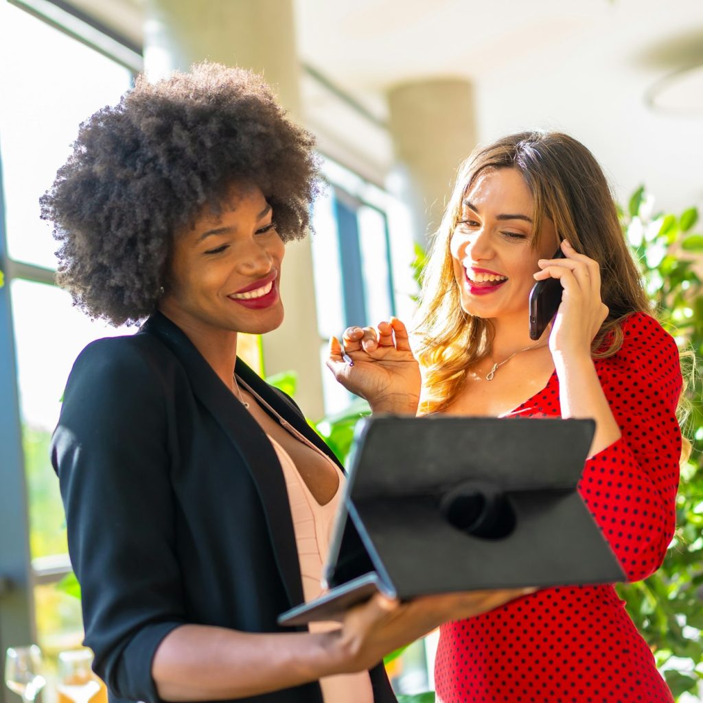 Caucasian blonde and black skinned girl with afro hair making a work video call with a tablet